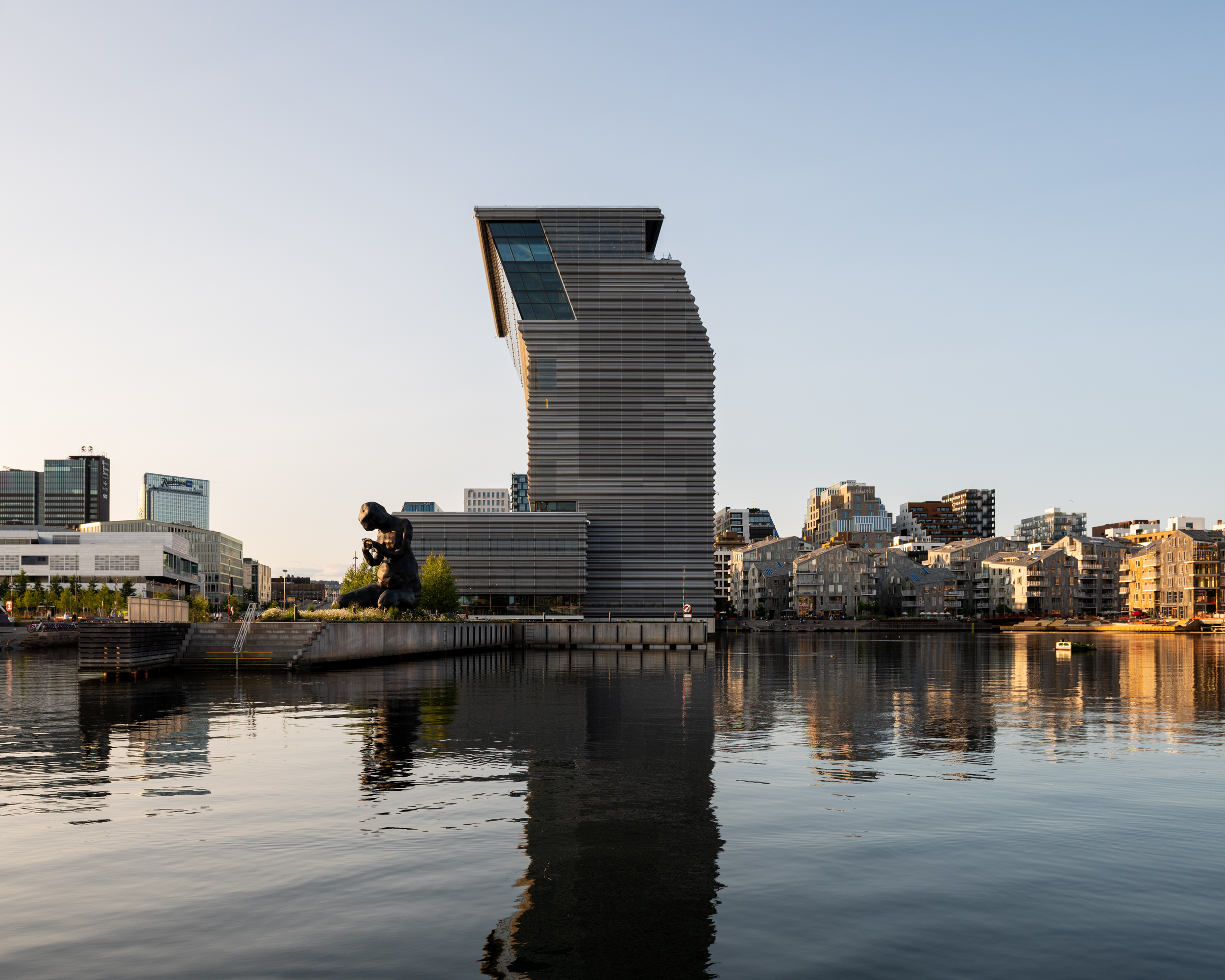 MUNCH seen from the water, with Bjørvika in the background. In the centre, the side view of the MUNCH building and the sculpture The Mother. Photograph.
