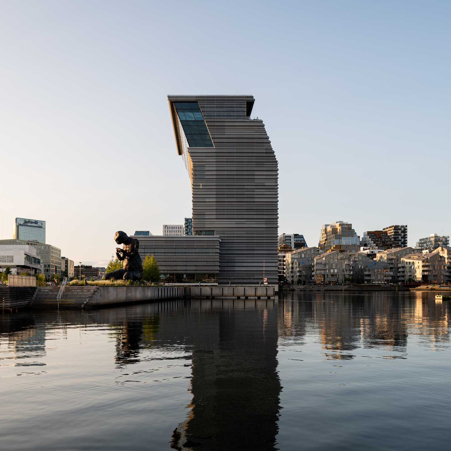 MUNCH seen from the water, with Bjørvika in the background. In the centre, the side view of the MUNCH building and the sculpture The Mother. Photograph.