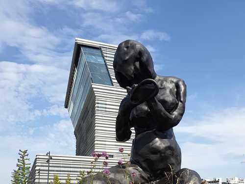 Du ser skulpturen Moren, en mørk bronseskulptur av kunstneren Tracy Emin, som er 9 meter høy. I bakgrunnen ser du MUNCH-bygget og blå himmel. Fotografi