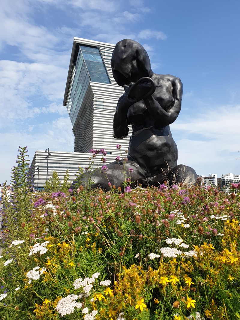 Du ser skulpturen Moren, en mørk bronseskulptur av kunstneren Tracy Emin, som er 9 meter høy. I bakgrunnen ser du MUNCH-bygget og blå himmel. Fotografi
