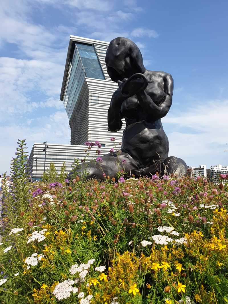 Du ser skulpturen Moren, en mørk bronseskulptur av kunstneren Tracy Emin, som er 9 meter høy. I bakgrunnen ser du MUNCH-bygget og blå himmel. Fotografi