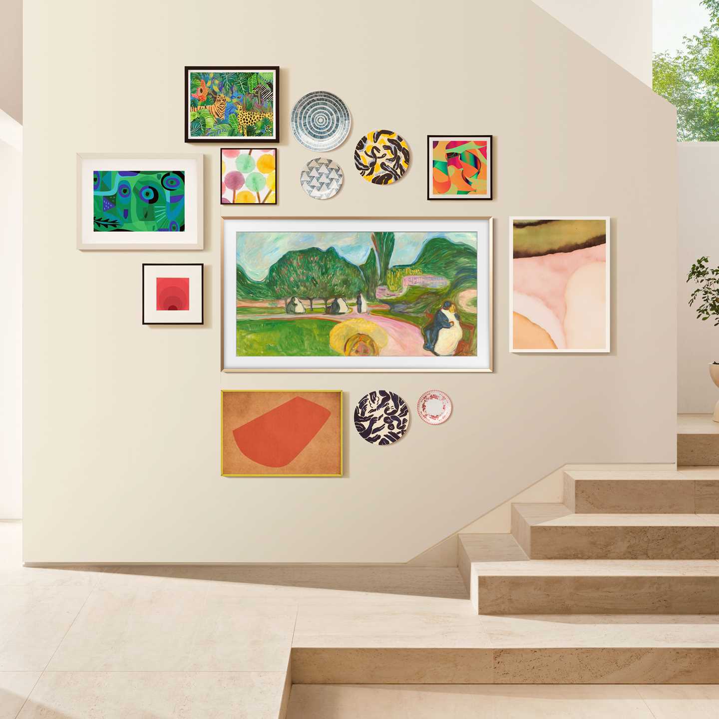 A wall inside a home displaying many different pictures. One of the images is a Samsung The Frame TV showing Kissing Couple in the Park by Edvard Munch. Photograph.