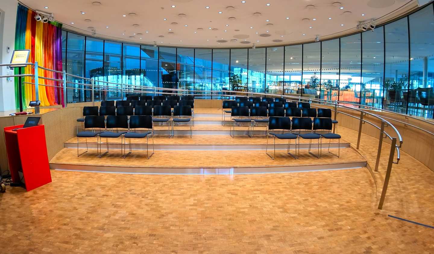 The Amfi hall at MUNCH. A circular room with windows all around. In the middle are four rows of chairs. Photograph.