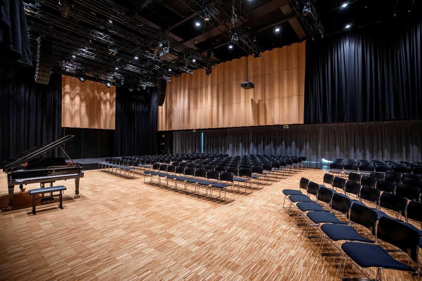 MUNCH’s banquet hall set up with a grand piano and rows of chairs arranged on three sides. Photograph.