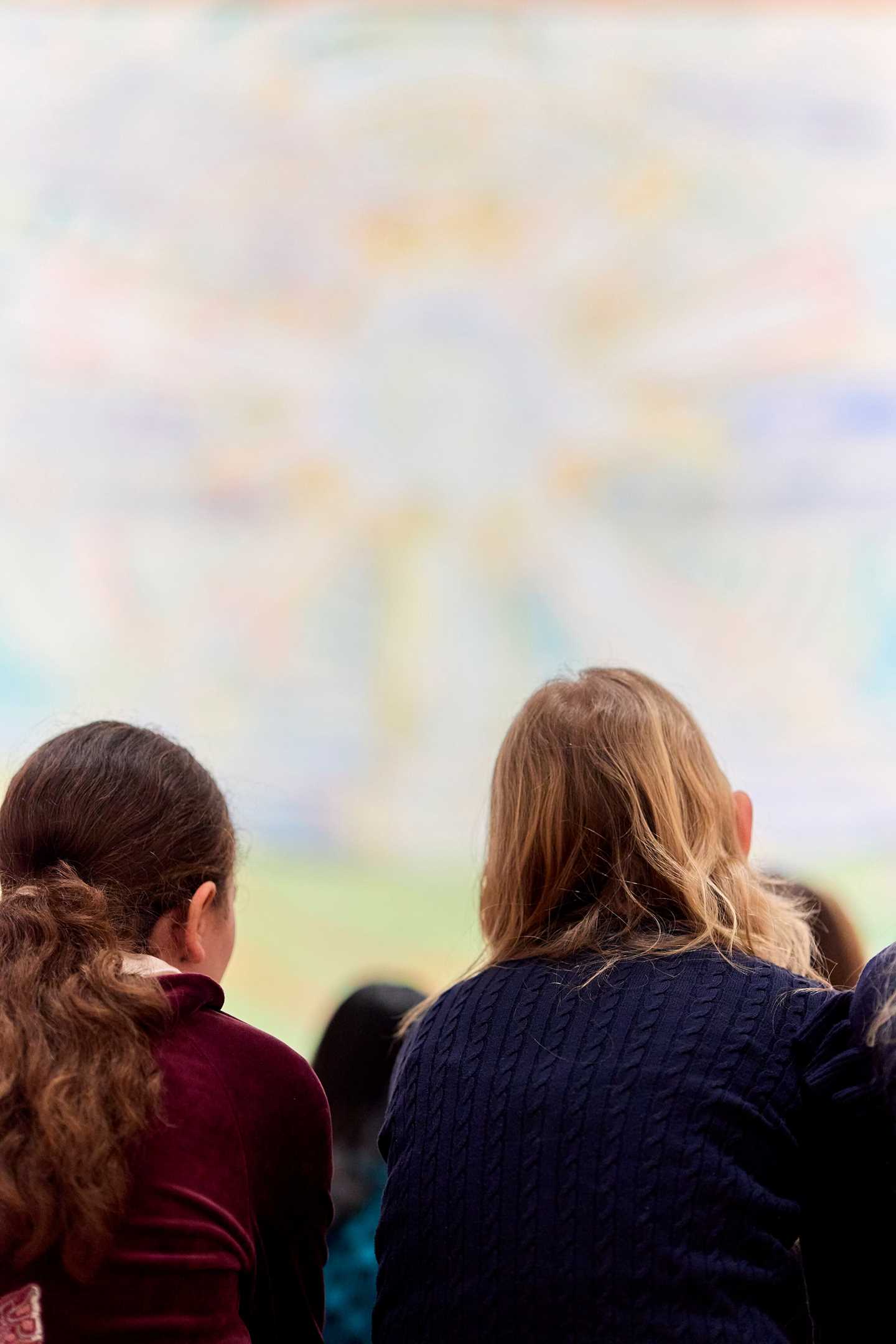 To jenter sitter med ryggen mot kamera og ser på Solen av Edvard Munch. Fotografi