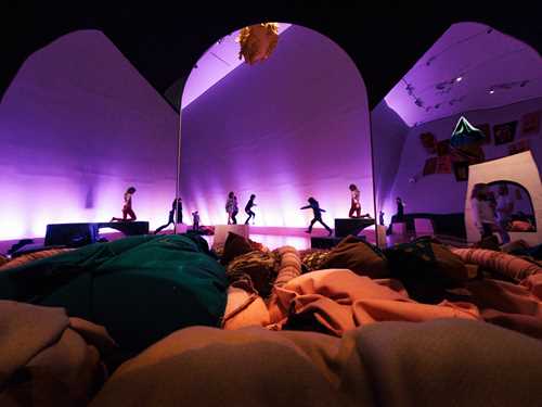 Barn leker i Kaoskammeret, de løper rundt i en fargerik verden med lilla lys, portaler og masse store puter og tekstilfigurer på bakken