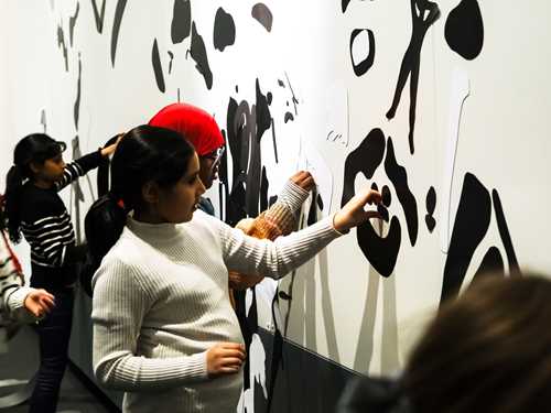 Fire barn som fester svarte magneter på en hvit vegg. Foto