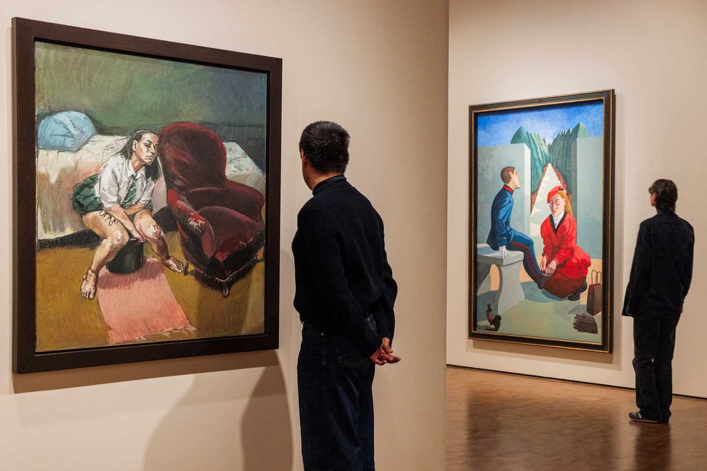 To mennesker står med ryggen mot kamera og betrakter to verk av Paula Rego. Fotografi
