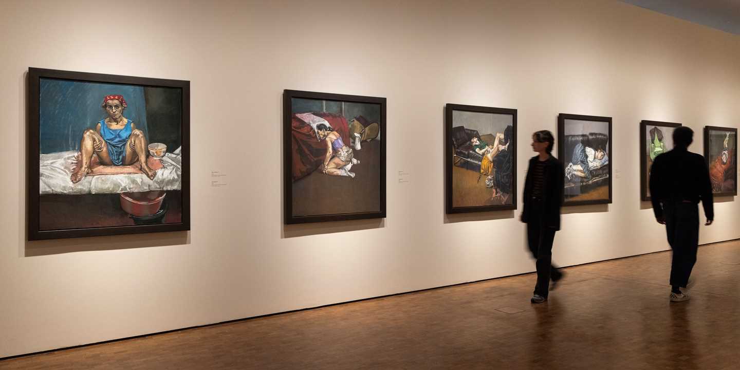 Bilde fra utstillingssal som viser verk av Paula Rego. I dette bildet er det seks verk fra Regos abortserie som henger på hvite vegger. To mennesker går gjennom salen. Fotografi