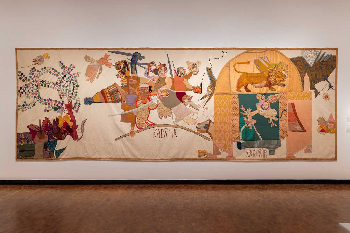Et stort tekstilverk av Paula Rego dekker en stor vegg i en utstillingssal. Fotografi