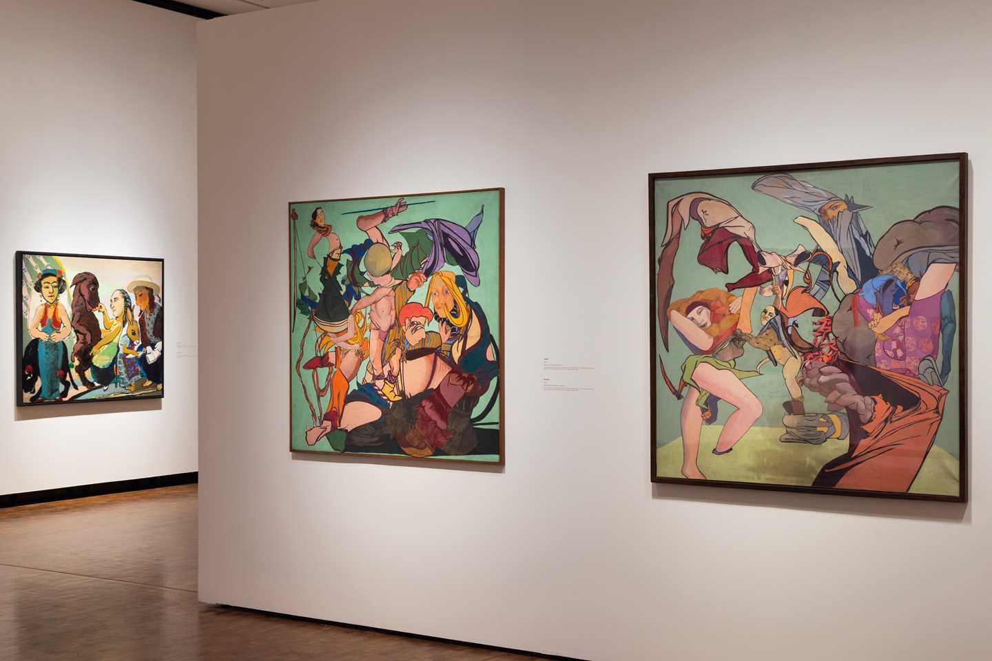 A view from an exhibition gallery showing works by Paula Rego. In this image, three colourful works hang on white walls. Photograph