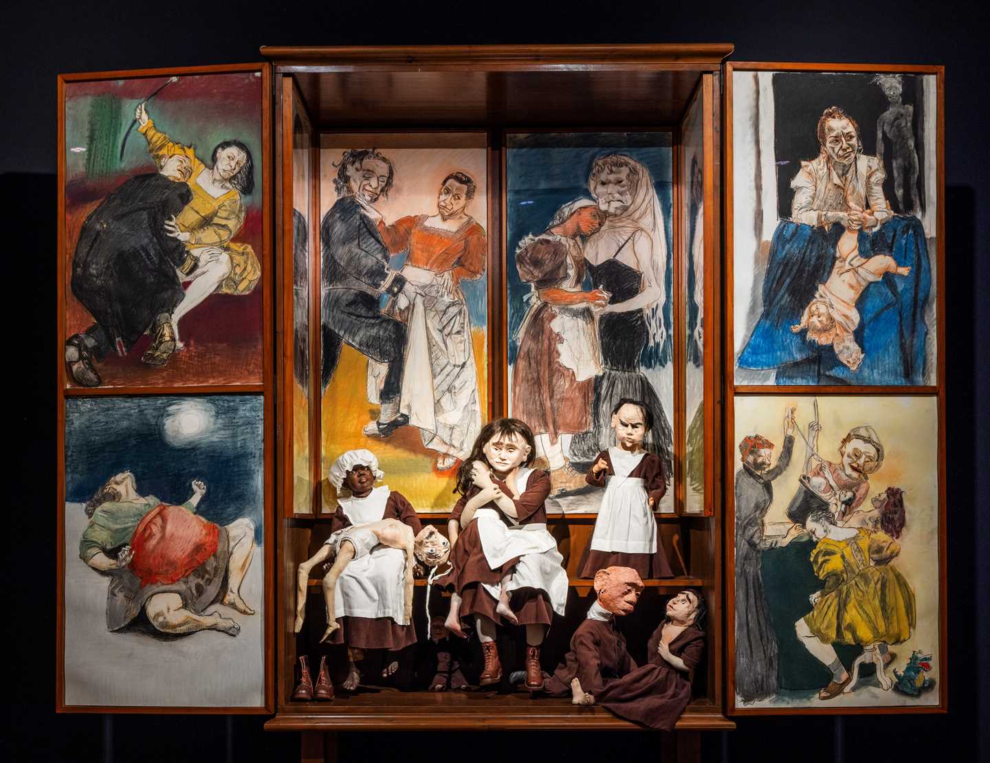 En altertavle med seks ulike pasteller og syv dukker i tekstil av Paula Rego. Fotografi