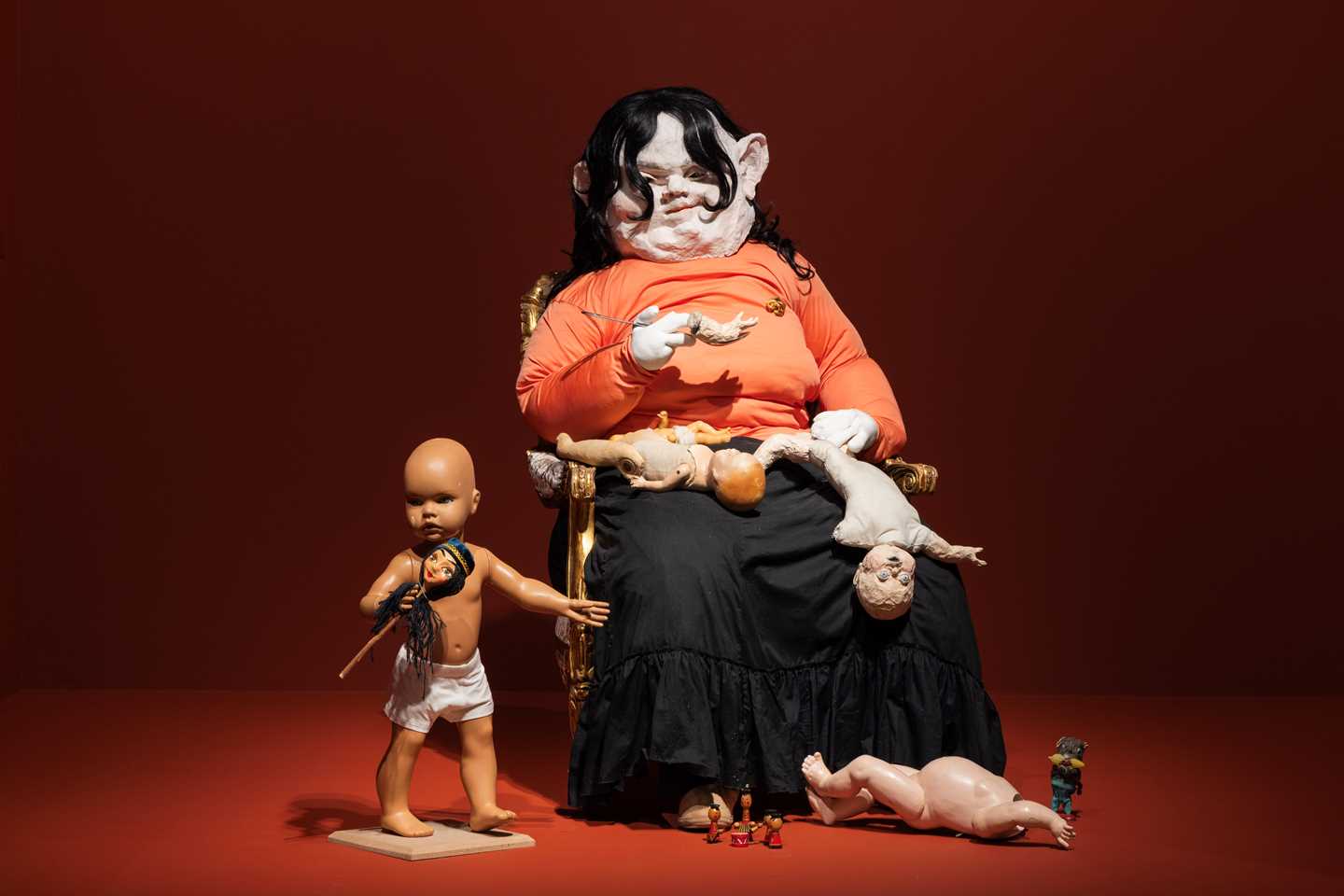 En skulptur av en kvinnelignende skikkelse, som sitter og spiser kroppsdeler av barn som ligger rundt henne. Ett av barna er ikke spist av enda og står på gulvet ved siden av kvinneskikkelsen. Fotografi