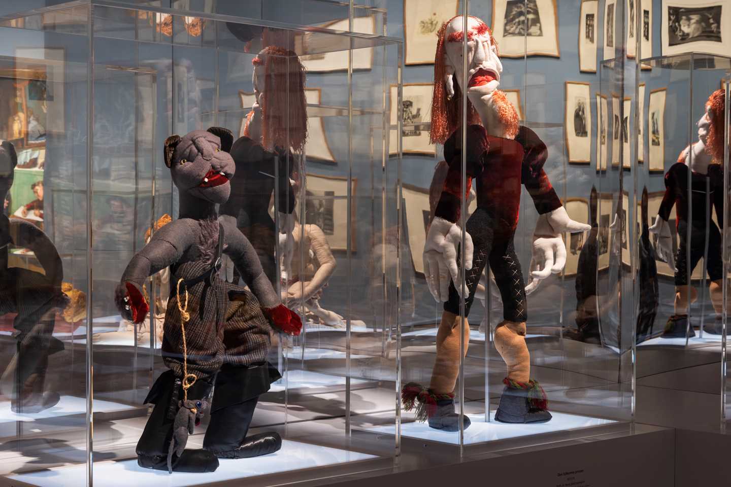 To tekstilskulpturer står i hvert sitt glassmonter med et stort speil montert bak. Fotografi