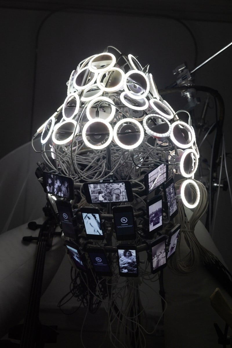 Sirkler av lysdioder med hvitt lys, ledninger og mobilskjermer er satt sammen slik at det har samme form som et Buddha-hode. Dette er et nærbilde av en del av installasjonen. Fotografi