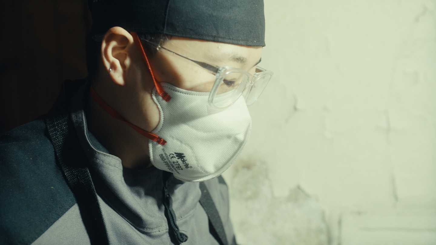 Nærbilde av kunstneren Kim Hankyul i profil. Han har på seg et svart hodeplagg, briller og et hvitt munnbind. Fotografi