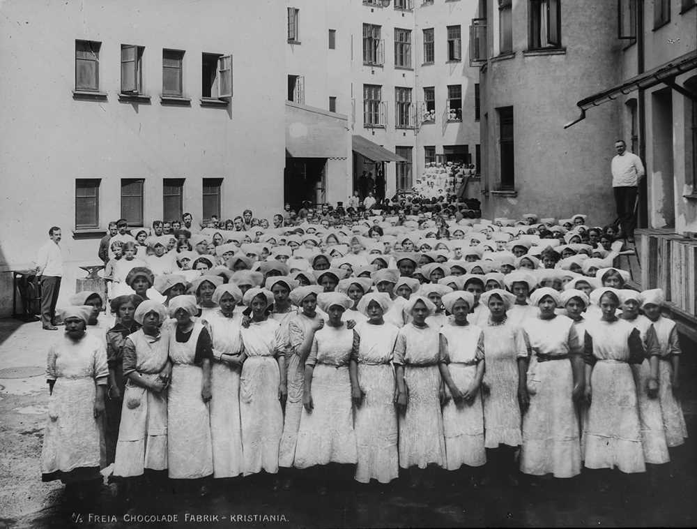 Black and white photo of women in uniforms working at Freia sjokoladefabrikk