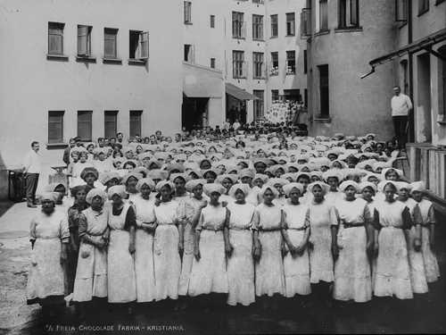 Black and white photo of women in uniforms working at Freia sjokoladefabrikk