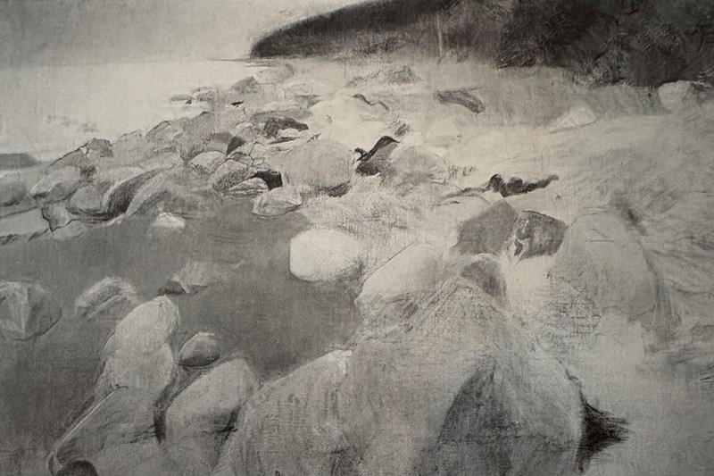 A white, rocky beach curves gently inward across the image. In the background, a dark mountain rises from the shoreline.